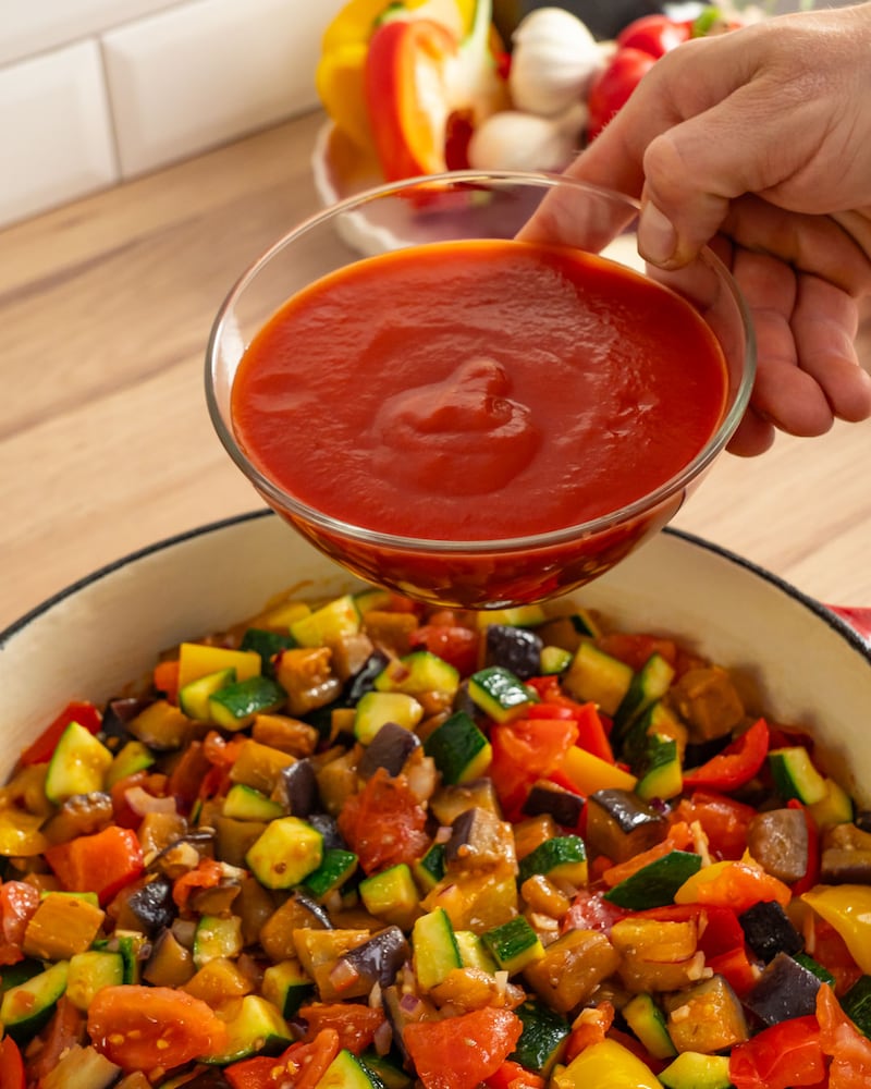 Dieses Bild zeigt wie die passierten Tomaten hinzugegebn werden.