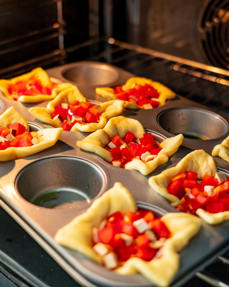 Dieses Bild zeigt wie die Pizzamuffins in den Ofen geschoben werden.