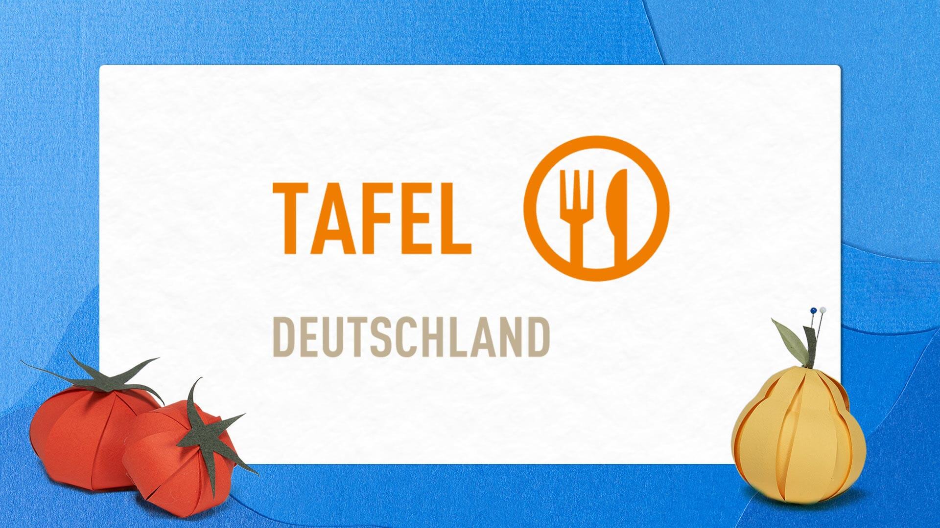 Tafel-Logo auf weißem Papier mit Obst und Gemüse aus Papier vor blauem Hintergrund