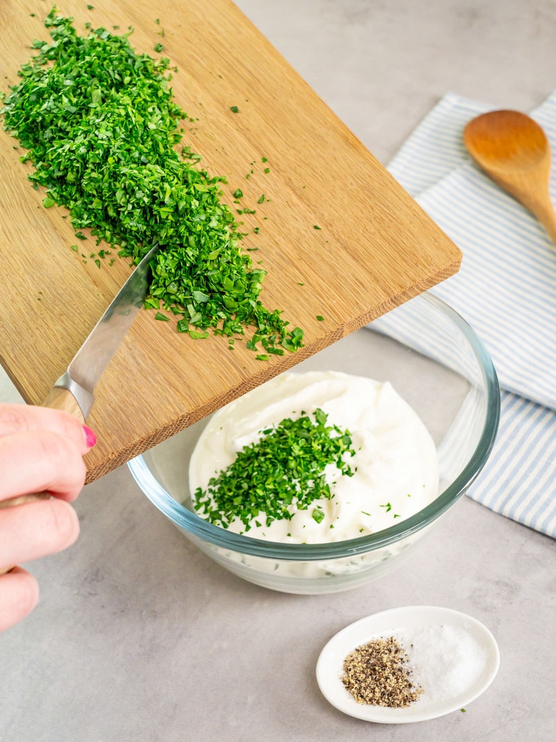 Dieses Bild zeigt wie die Petersilie in den griechischen Joghurt gegeben wird.