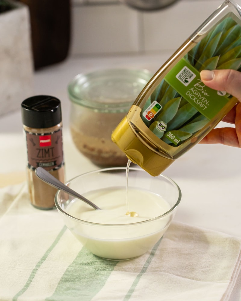 Dieses Bild zeigt wie Joghurt mit Agavendicksaft gesüßt wird.