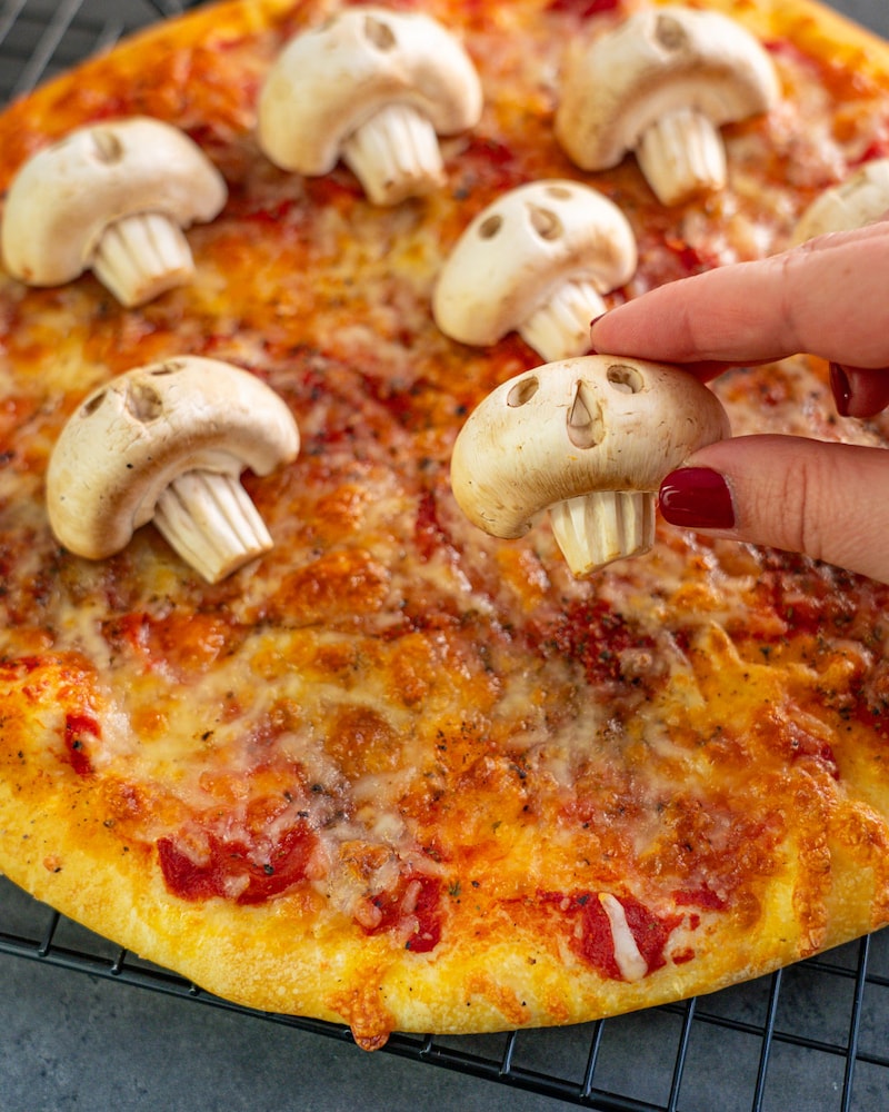 Dieses Bild zeigt wie die Pilze auf die Pizza gegeben werden.