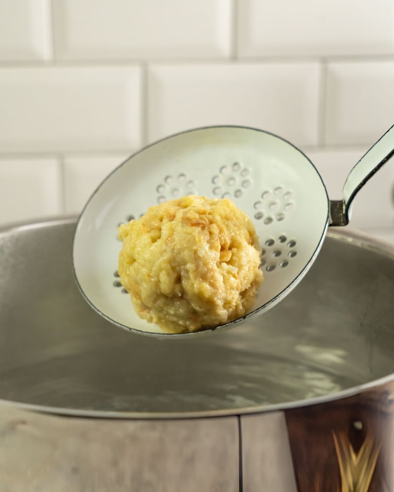 Dieses Bild zeigt wie die Knödel in das Wasser gegeben werden.