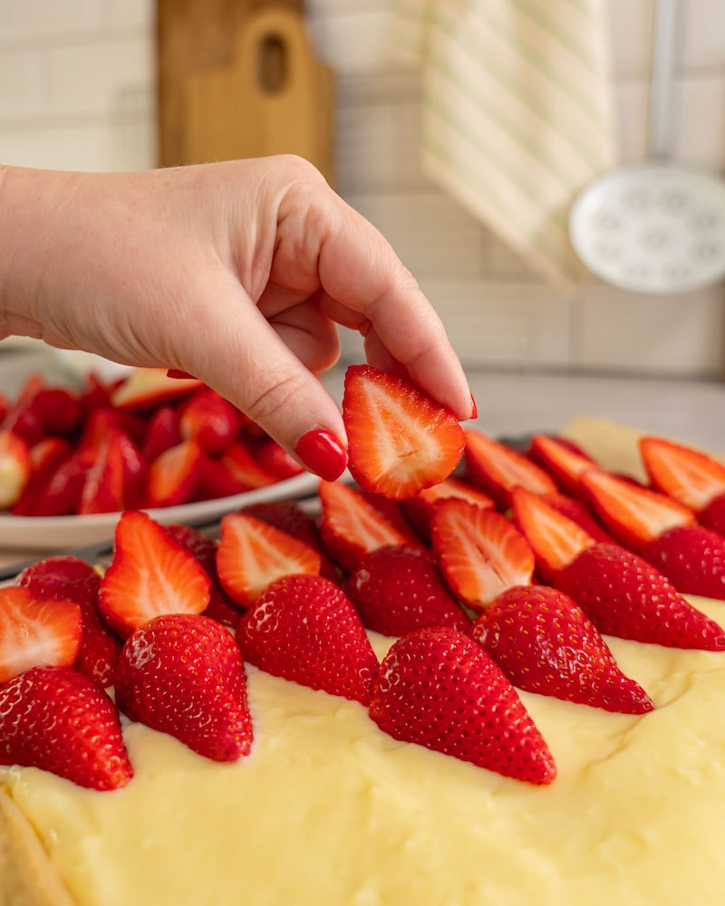 Dieses Bild zeigt wie die Erdbeeren auf den Kuchen gelegt werden.