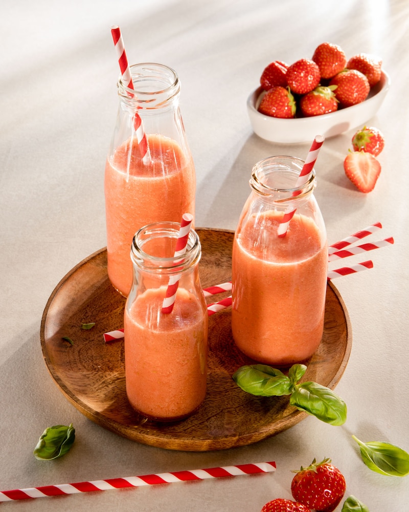 Das Bild zeigt eine Collage. Ein selbstgemachter Honigmelonen-Erdbeer-Smoothie in Fläschchen.