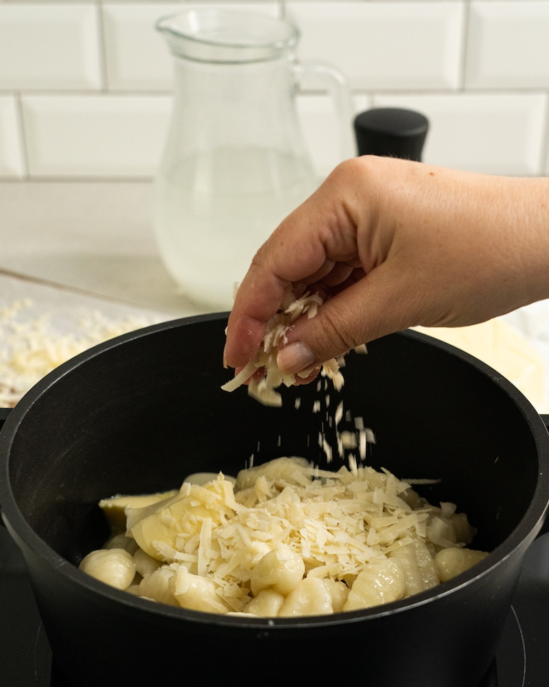 Auf diesem Bild siehst du wie die Gnocchi mit Käse bestreut werden.