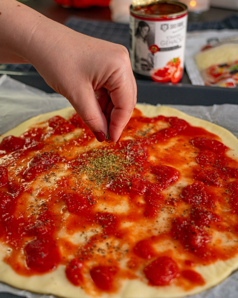 Dieses Bild zeigt wie der Oregano auf die Pizza gegeben wird.