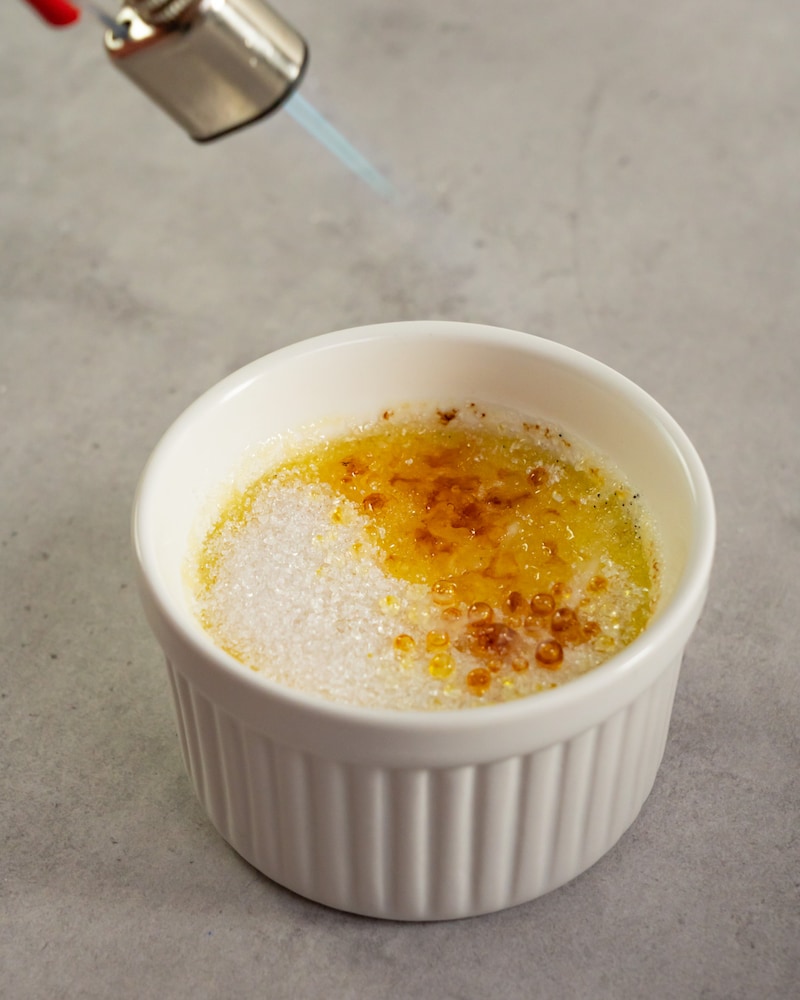 Dieses Bild zeigt wie die Creme Brulee mit dem Flambierbrenner karamellisiert wird.