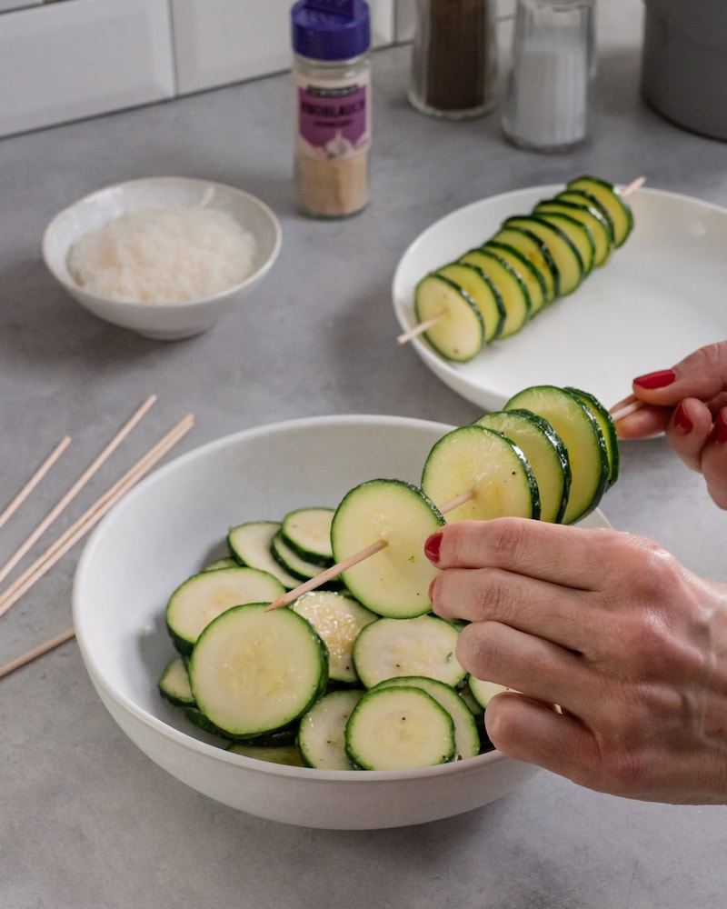 Dieses Bild zeigt, wie die Zucchini aufgespießt wird.