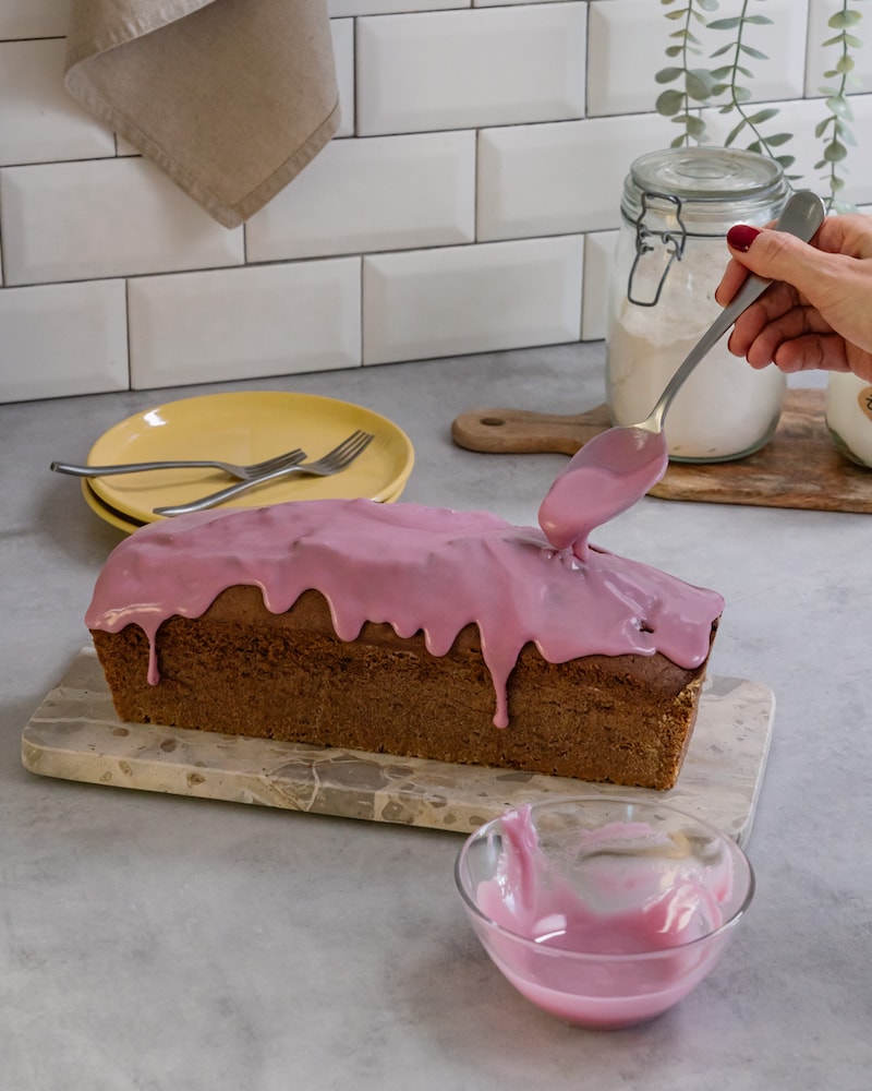 Diese Bild zeigt wie der fertige Kuchen mit pinker Glasur bestrichen wird.