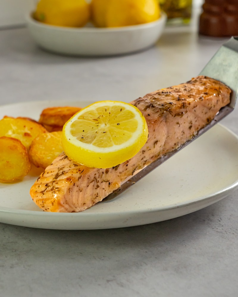 Dieses Bild zeigt wie der Lachs aus dem Ofen auf den Teller gegeben wird.