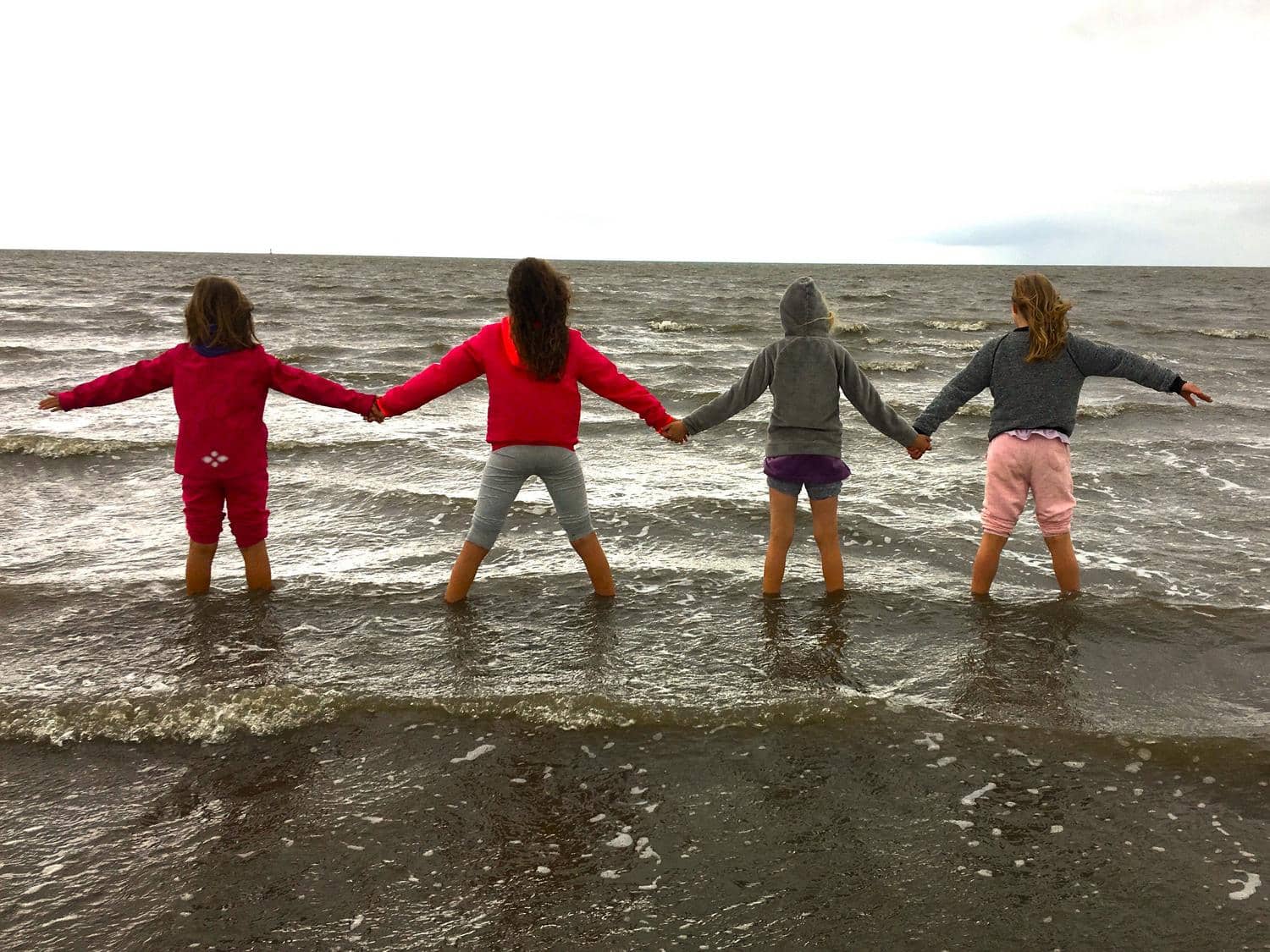 Kinder stehen Hand in Hand im Meer