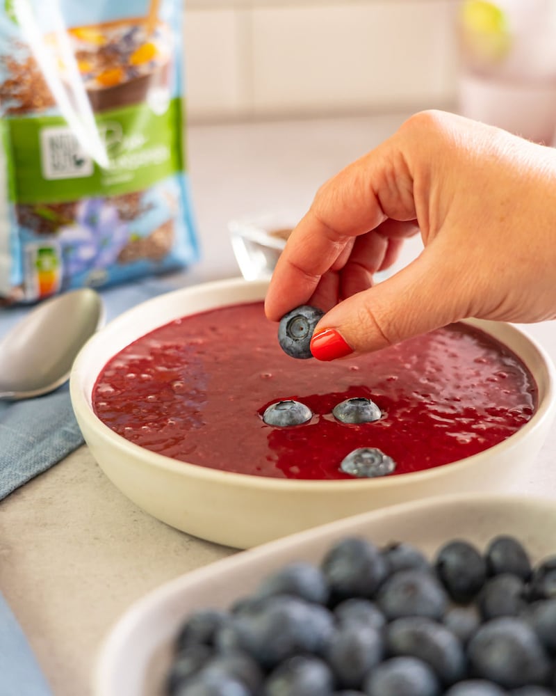 Dieses Bild zeigt wie die Blaubeeren auf die Smoothie Bowl gegeben wird.