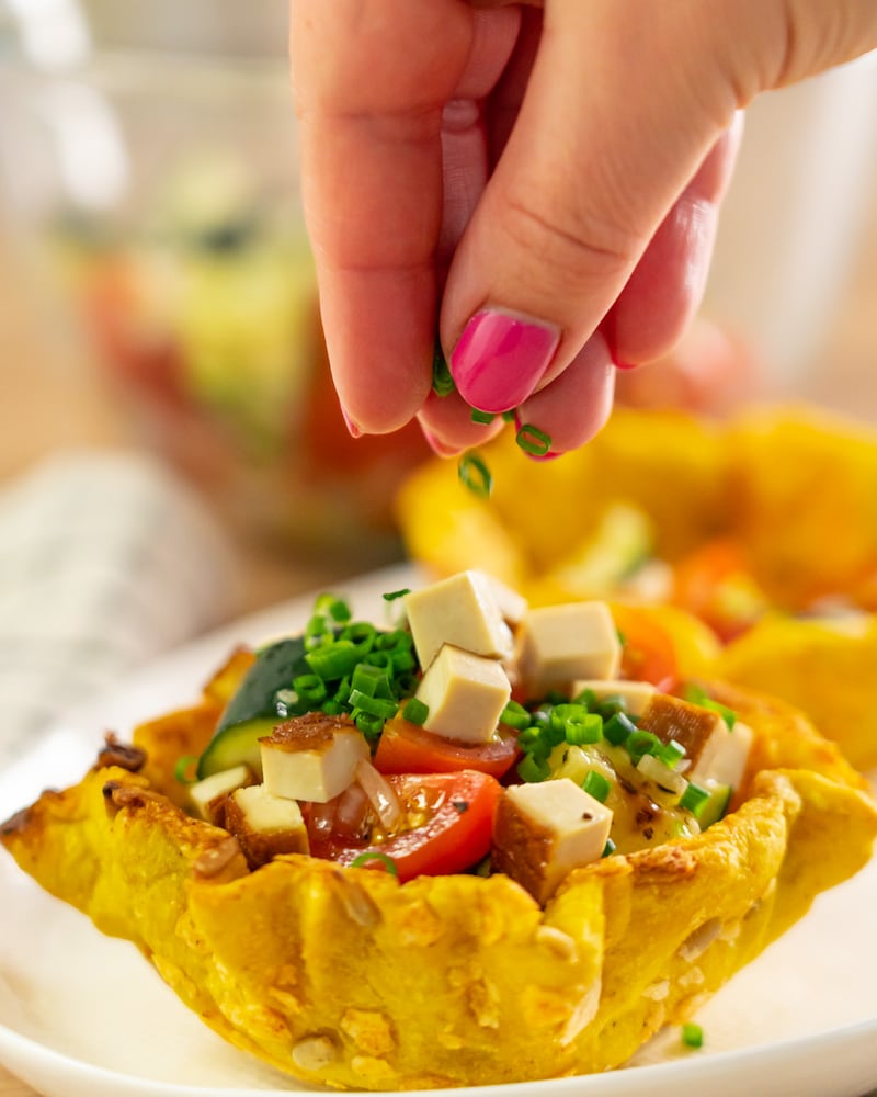 Dieses Bild zeigt, wie der Grill-Zucchini-Salat mit Räuchertofu in der Knusperschale verziert wird.
