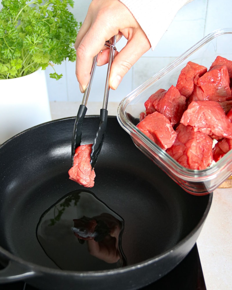 Dieses Bild zeigt wie das Fleisch in die Pfanne kommt.