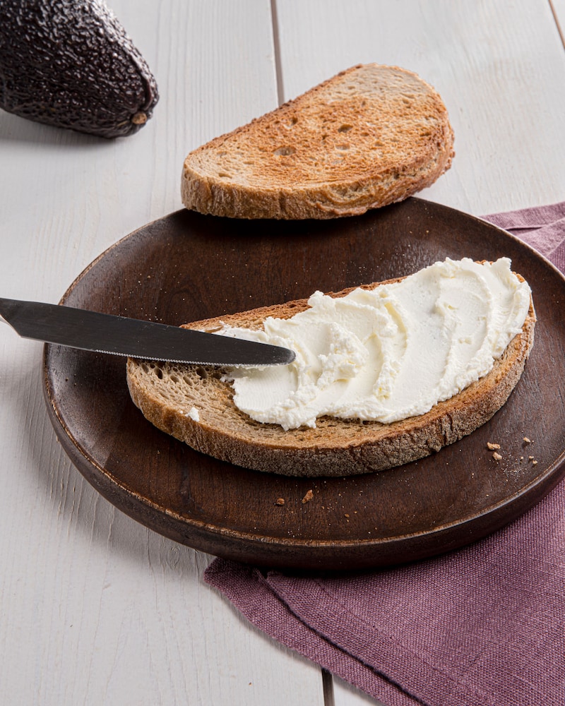 Dieses Bild zeigt wie das Brot mit Frischkäse bestrichen wird.