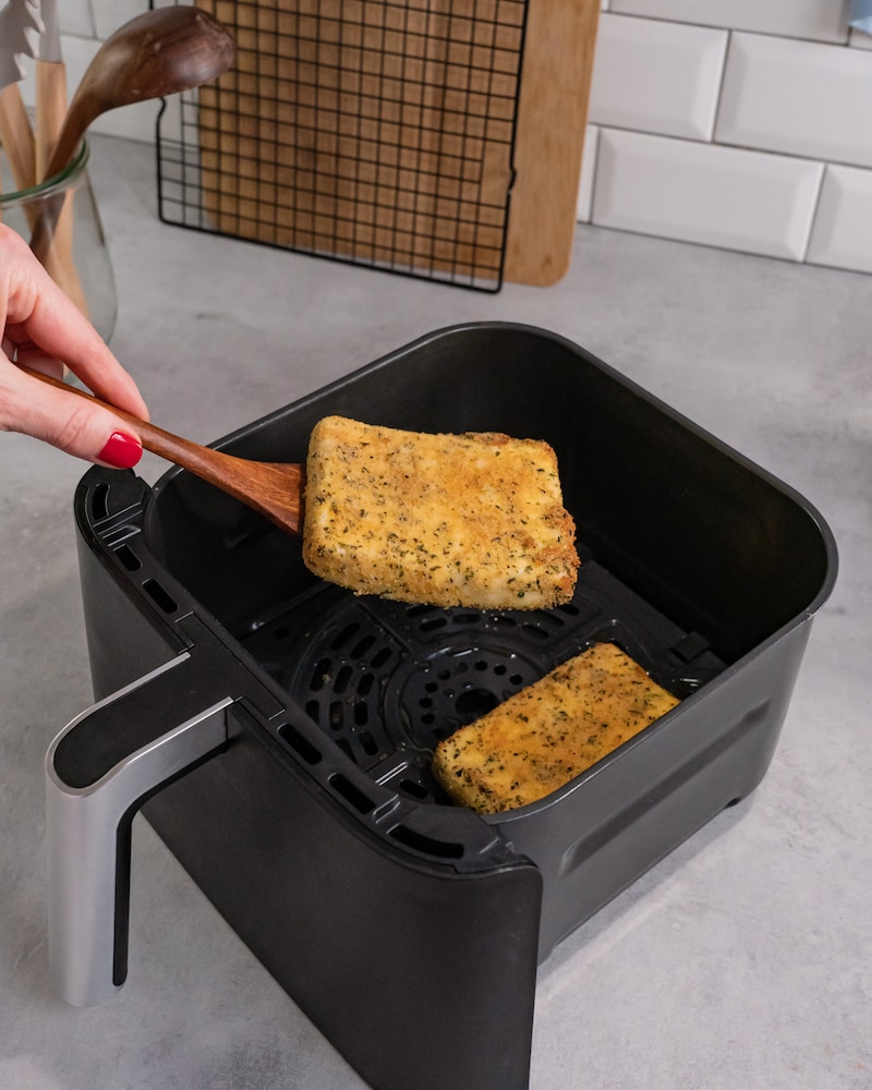 Dieses Bild zeigt wie der fertig panierten Feta aus der Heißluftfriteuse rausgeholt wird.