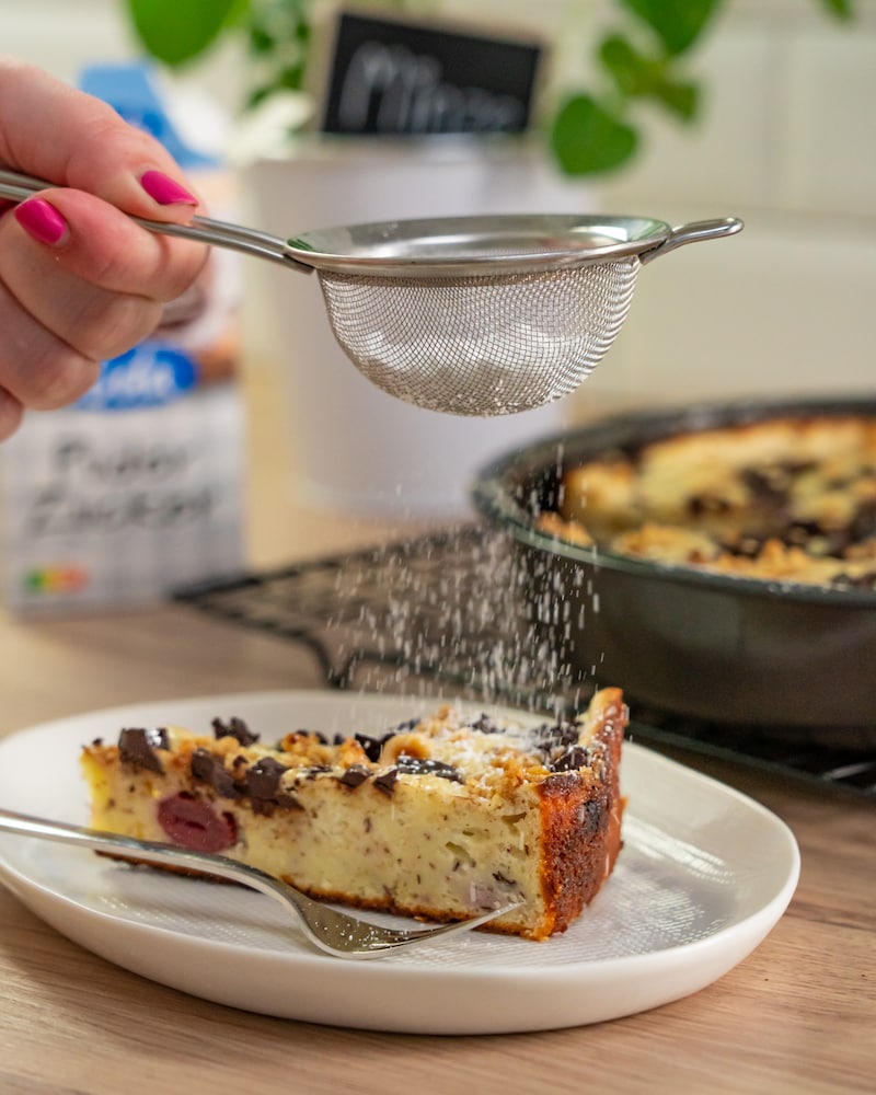 Dieses Bild zeigt, wie der Kuchen mit Puderzucker bestreut wird.