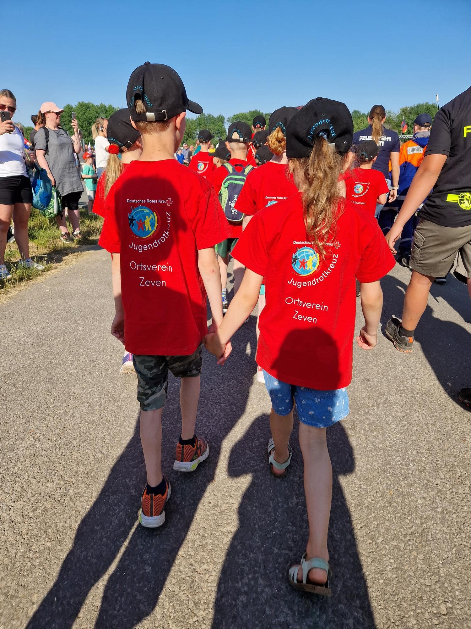 Kinder laufen Hand in Hand in Vereinskleidung