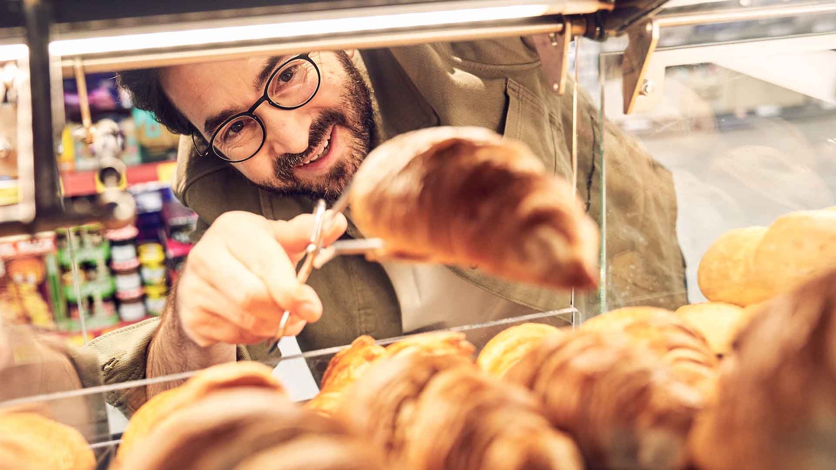 Ein Kunde bedient sich an den frischen Croissants aus der PENNY Backstation.