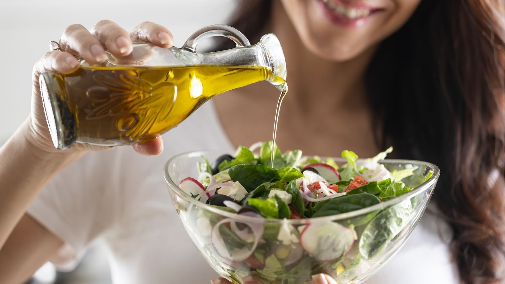 Frau fügt Öl zu Salat hinzu