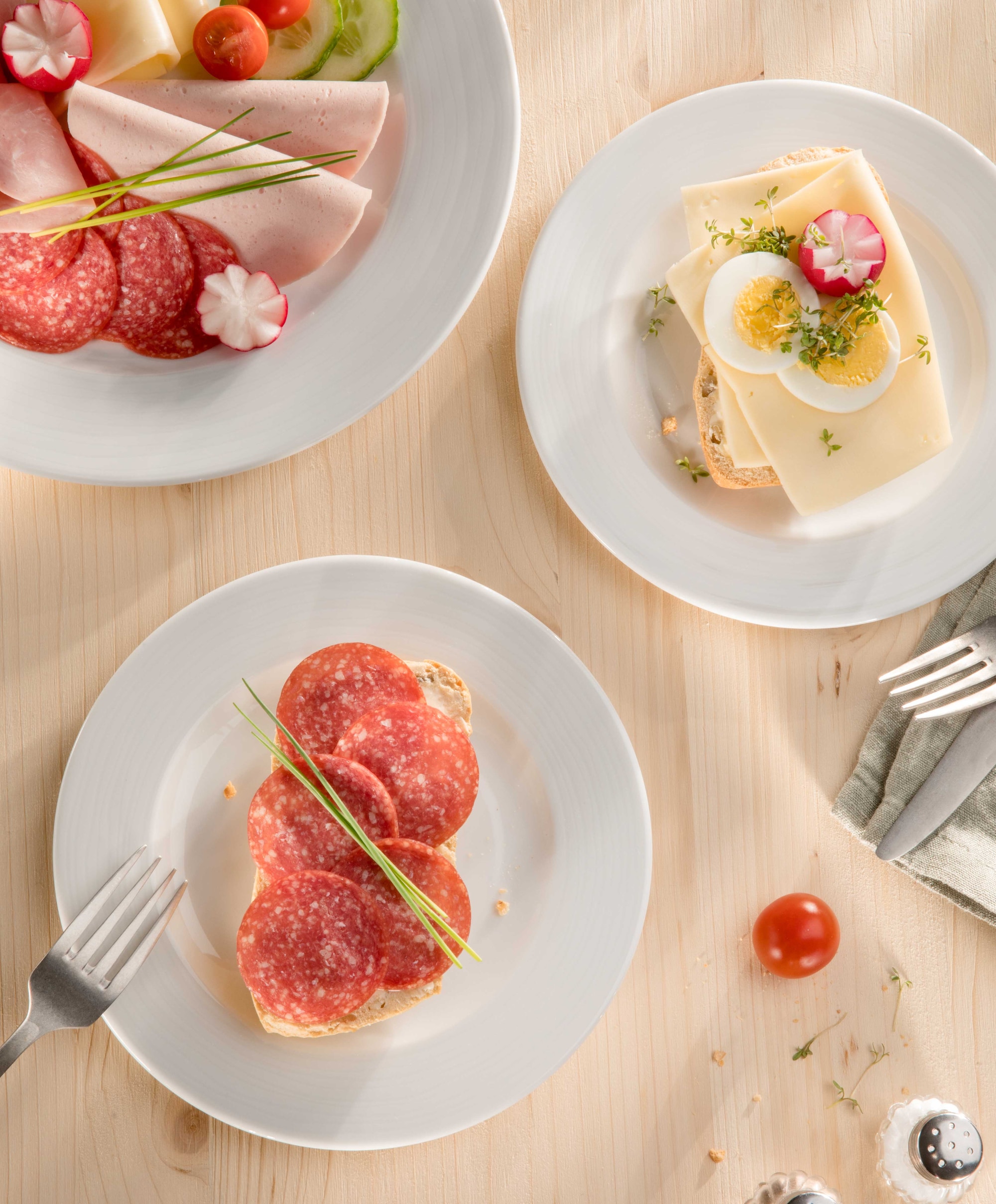 Dieses Bild zeigt ein paar Brötchen mit Wurst und Käse, zusammen mit Schnittlauch und Radieschen.