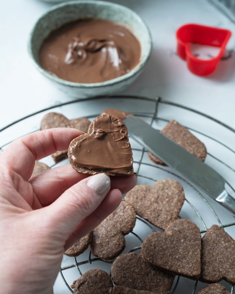 Dieses Bild zeigt wie die Herzen mit Nuss-Nougat-Creme bestrichen werden.