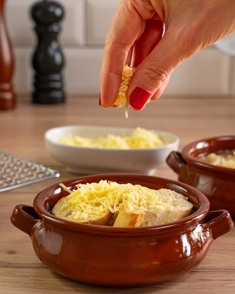 Dieses Bild zeigt wie der Käse auf die Suppe gegeben wird.