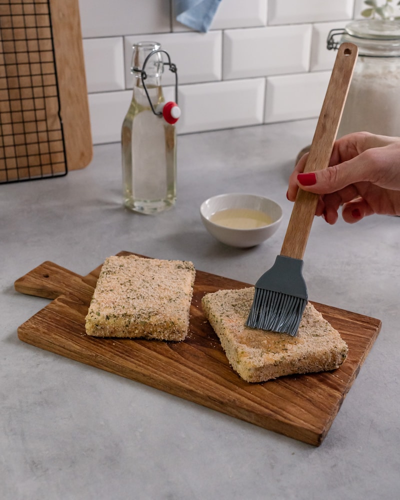 Dieses Bild zeigt, wie der Feta noch mit Öl bepinselt wird.