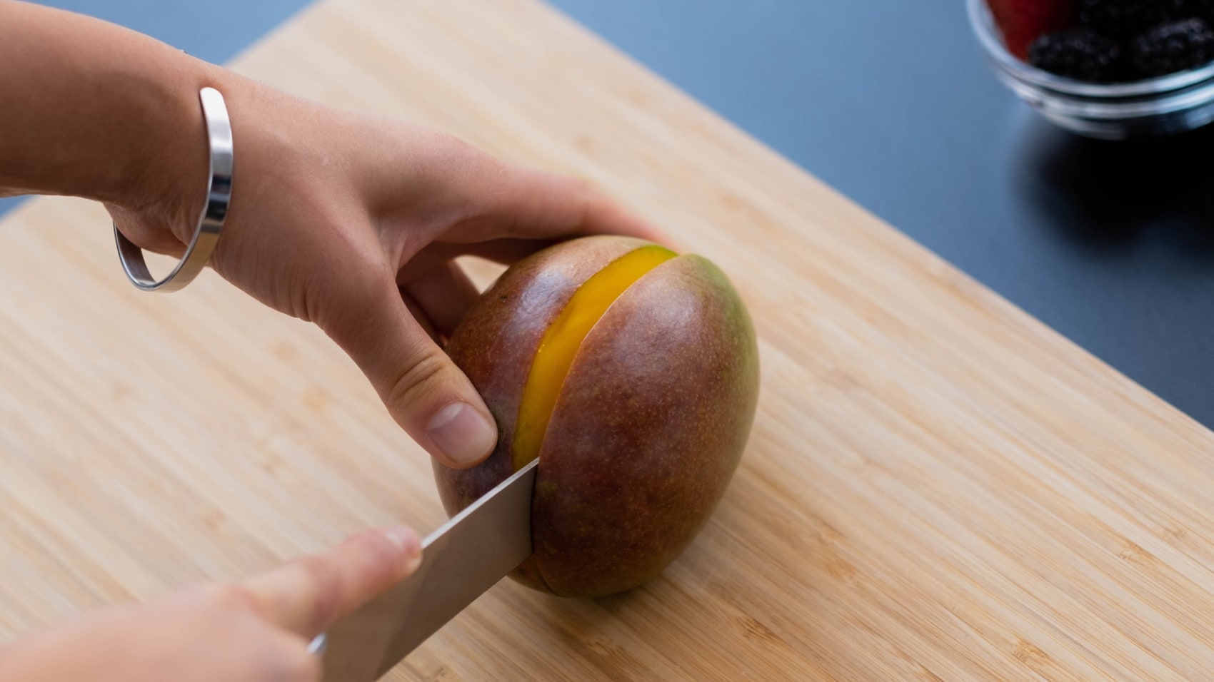 Eine Mango die der Länge nach halbiert wird.