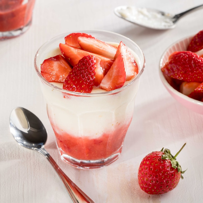 Das Bild zeigt einen Grießpudding in einem weißen Schälchen mit ein paar Erdbeeren oben drauf. 