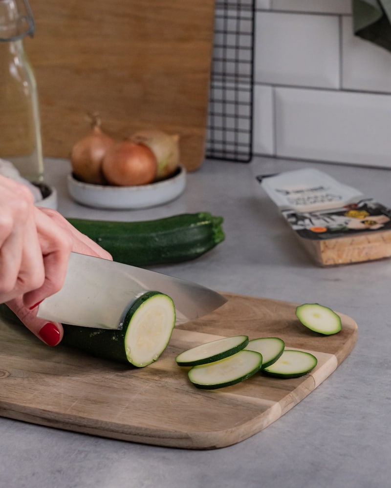 Dieses Bild zeigt, wie die Zucchini in dünne Taler geschnitten wird.