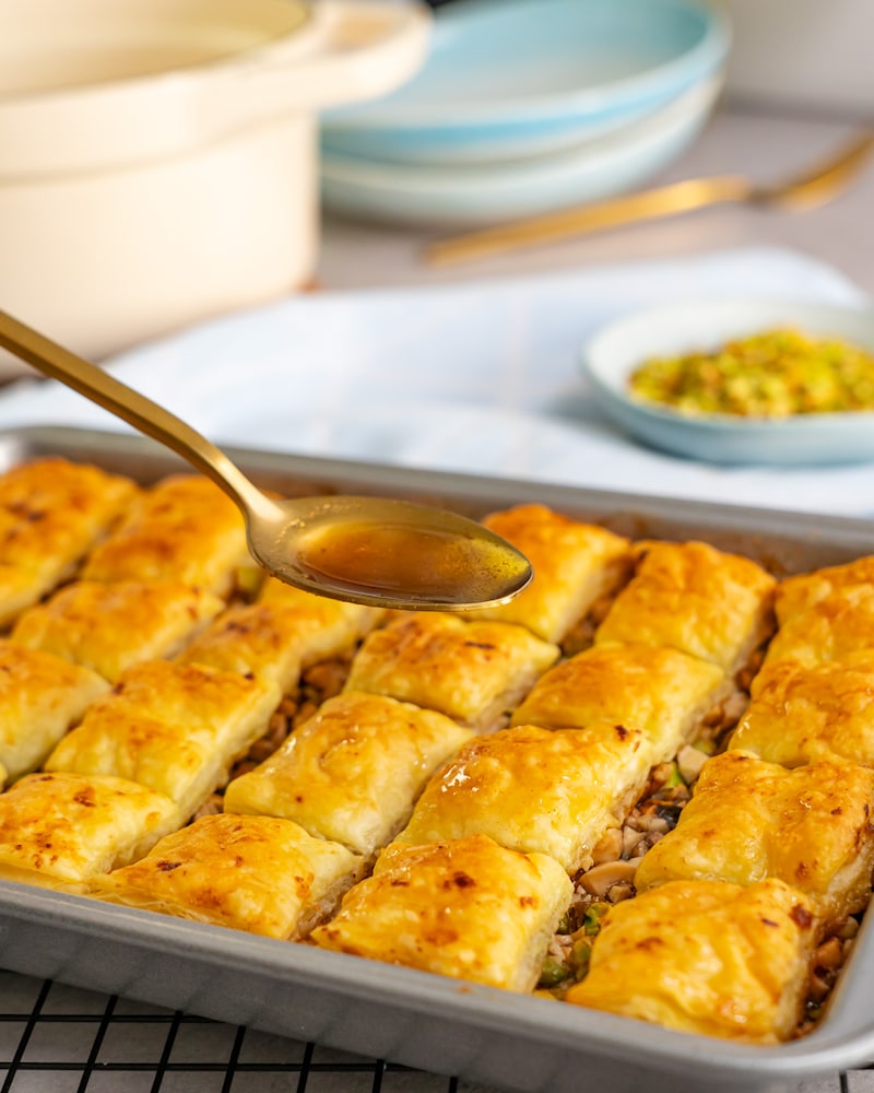 Dieses Bild zeigt wie der Sirup über das Baklava gegeben wird.
