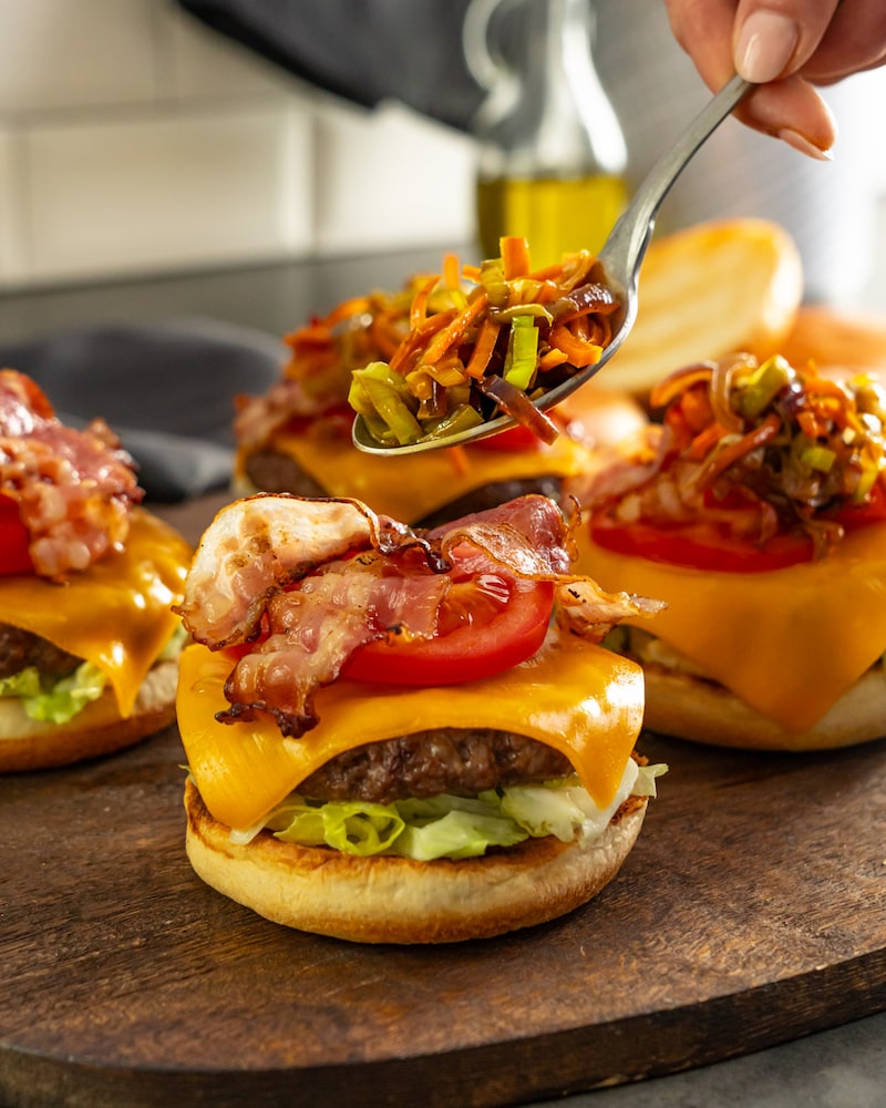 Dieses Bild zeigt wie das Biergemüse auf den Burger gegeben wird.