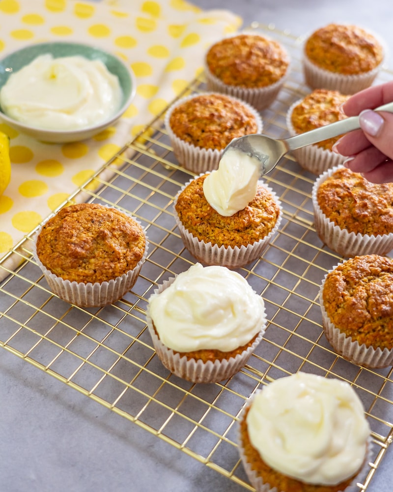 Dieses Bild zeigt wie das Frischkäse Topping auf die Muffins gegeben wird.