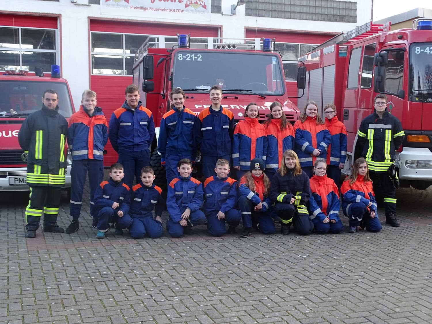 Kinder und Vereinsmitglieder in Uniform laecheln in die Kamera