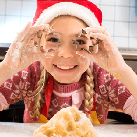 Kind mit Ausstechern in der Hand in der Küche