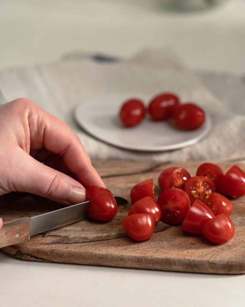 Auf diesem Bild siehst du wie Kirschtomaten geschnitten werden.