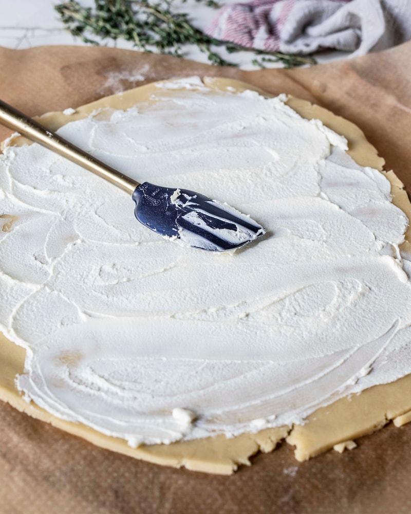 Dieses Bild wie der Teig mit Frischkäse bestrichen wird.