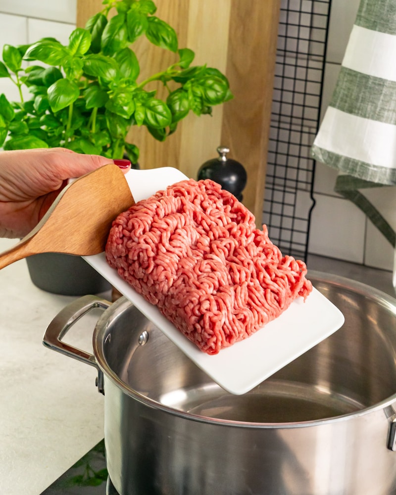 Dieses Bild zeigt wie das Fleisch in den Topf gegeben wird.