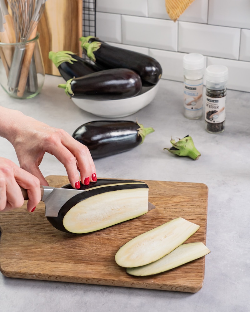 Dieses Bild zeigt wie die Aubergine in Scheiben geschnitten wird.