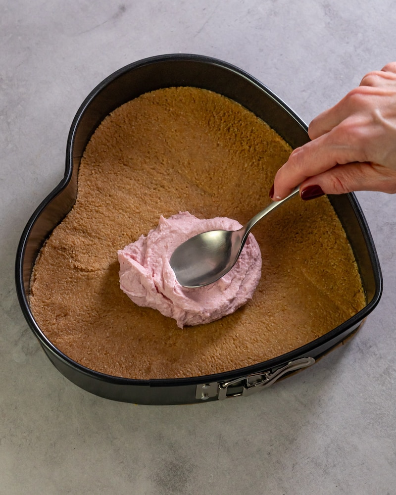 Dieses Bild zeigt wie das Himbeerpüree und die Sahne auf den Kuchen gegeben werden.