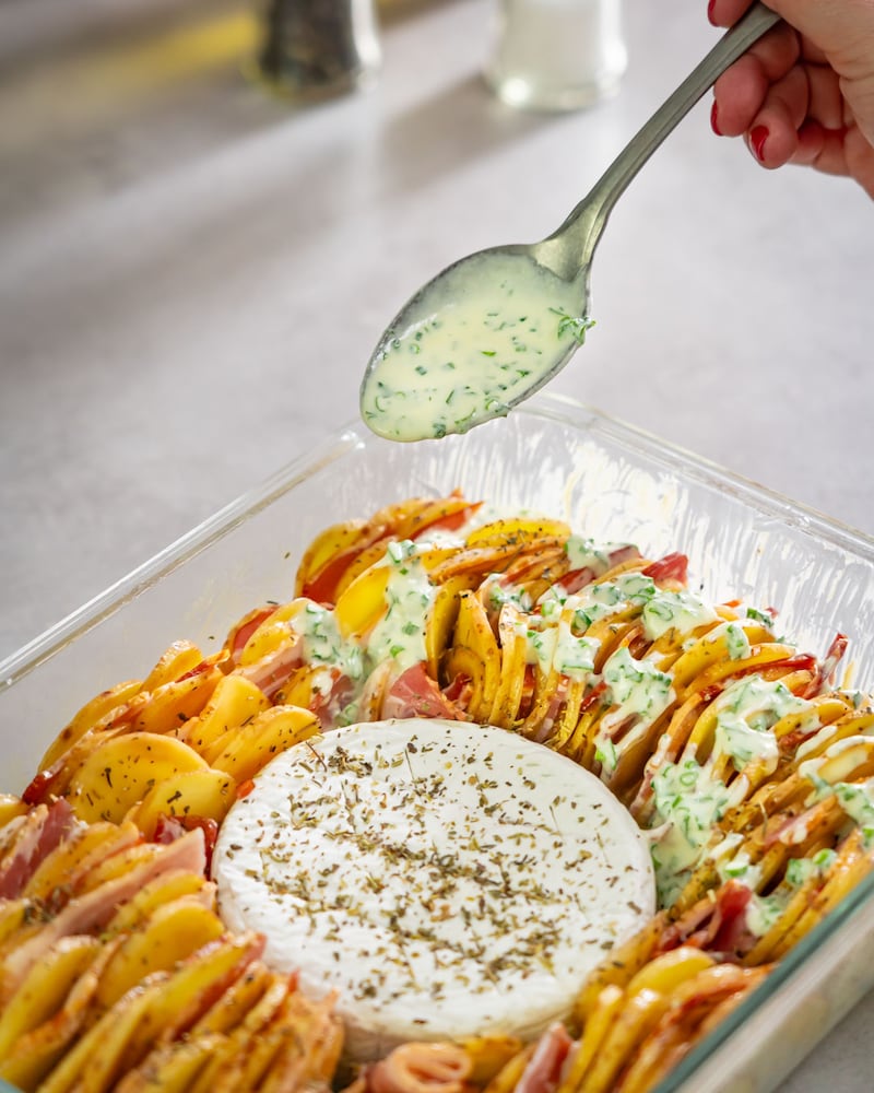 Dieses Bild zeigt wie die Sauce über den Kartoffelauflauf gegeben wird.