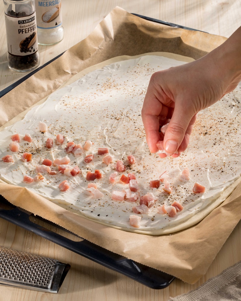Das Bild zeigt wie der Flammkuchen belegt wird.