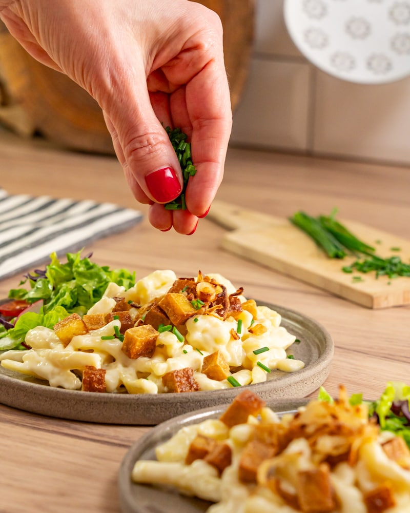 Dieses Bild zeigt wie der Schnittlauch über die Spätzle gegeben wird.