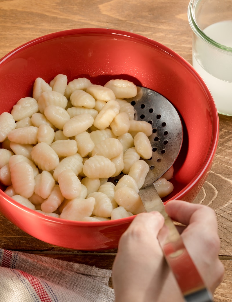 Auf diesem Bild siehst du Gnocchi die abgeschüttet werden.