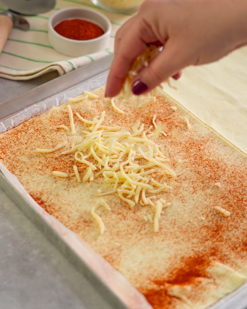 Dieses Bild zeigt das verteilen des Käse über dem Blätterteig.