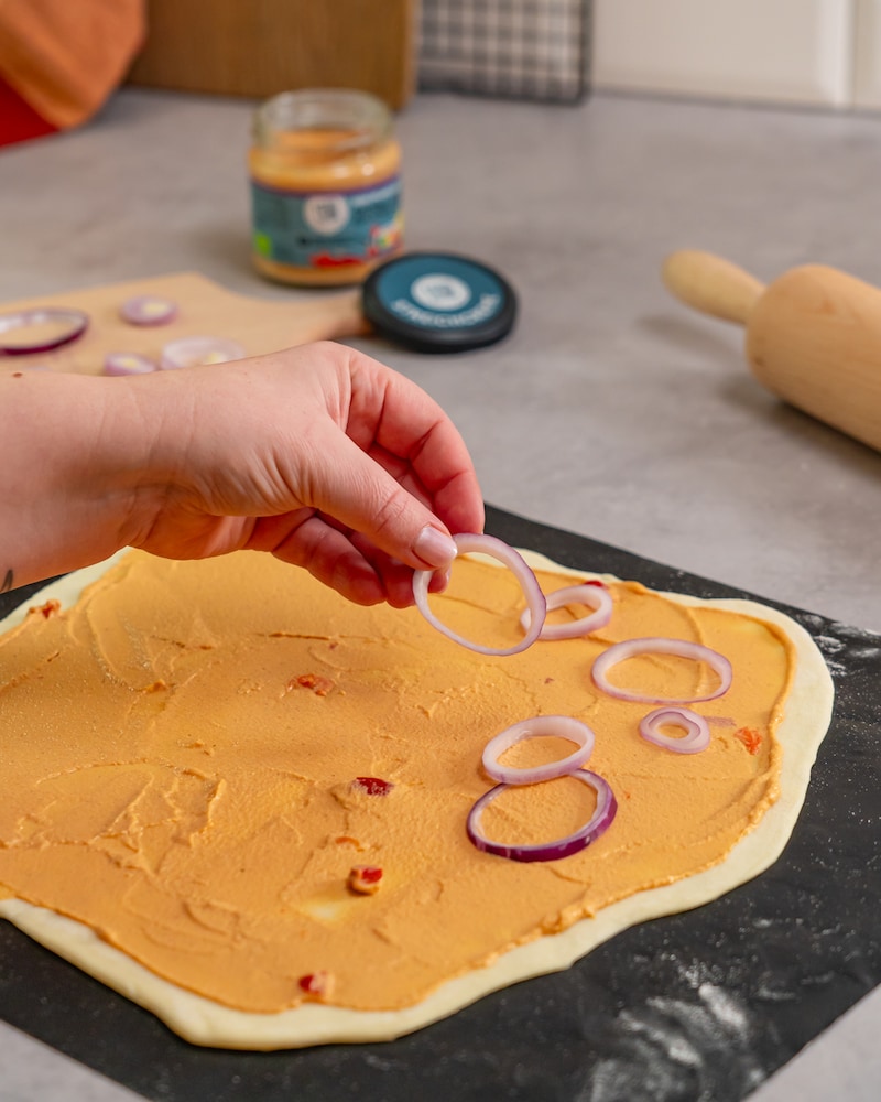 Dieses Bild zeigt das Belegen des Flammkuchen mit Zwiebeln.