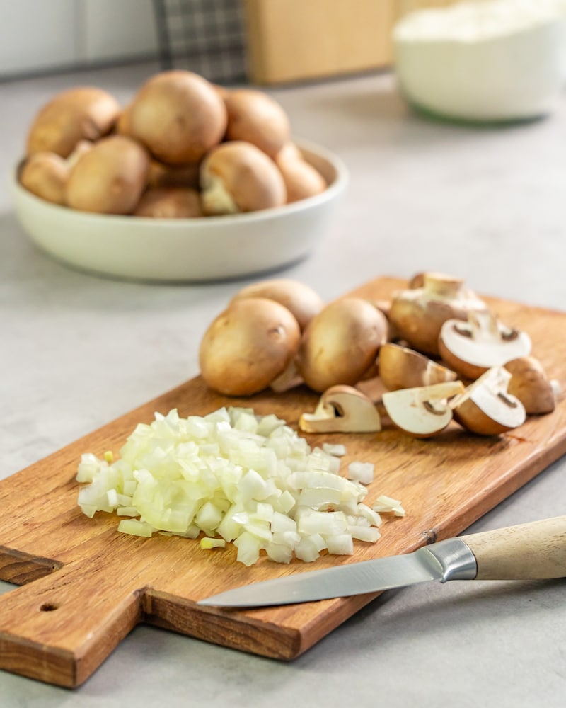 Dieses Bild zeigt wie die Zwiebeln und die Pilze geschnitten werden.