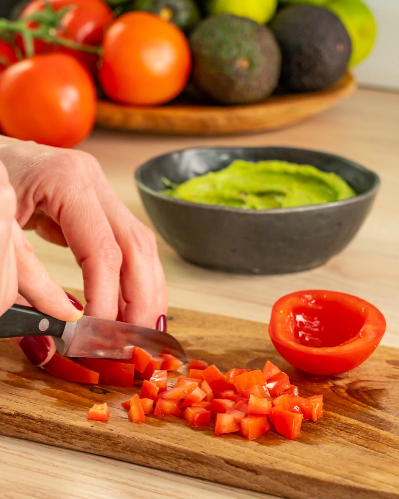 Dieses Bild zeigt wie ausgefüllte Tomaten in kleine Würfel geschnitten werden.